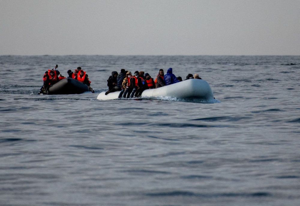 Two crowded inflatable boats filled with people in life vests on the open sea.