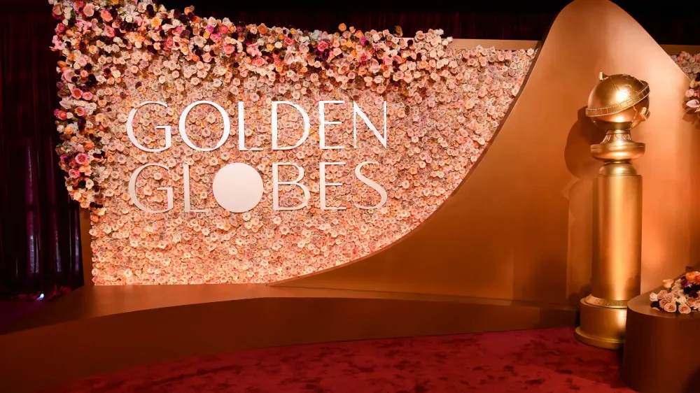 Golden Globes backdrop with floral wall, event logo, and golden award trophy.