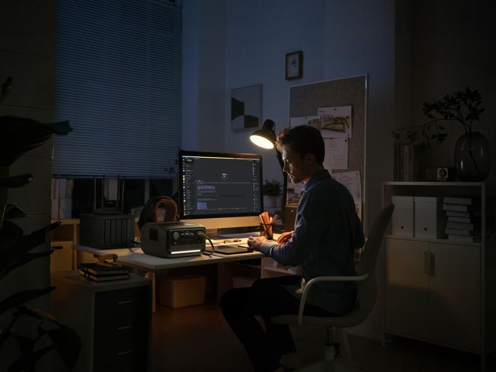 Man coding on a computer in a dimly lit office at night.
