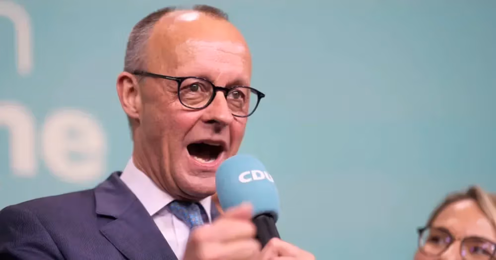Man in glasses speaking passionately into a CDU microphone at a political event.