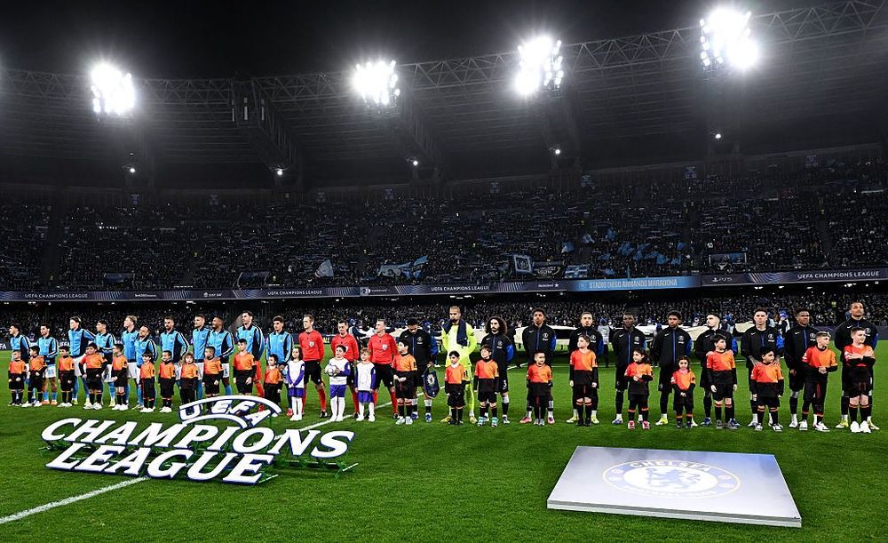 Children and football players stand on a stadium field with a large Champions League logo.
