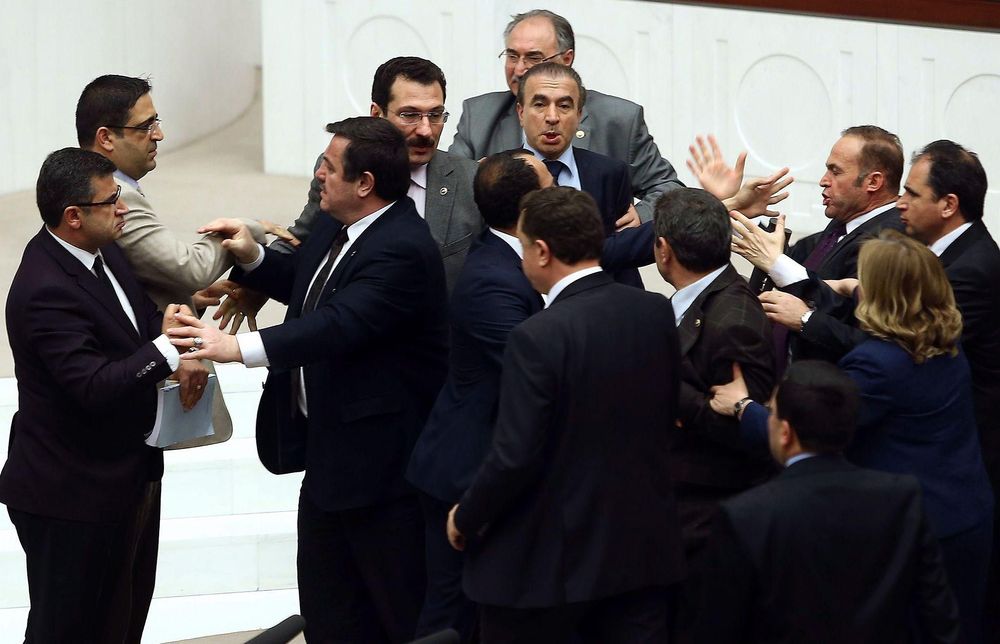 Group of men in suits engaged in a heated argument and pushing each other in a formal setting.