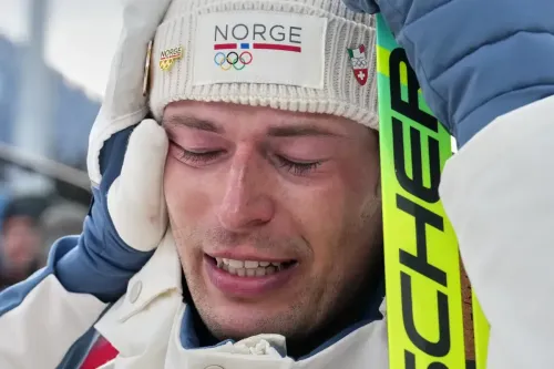 Norwegian athlete in white cap, labeled NORGE, looks emotional and covers his face.