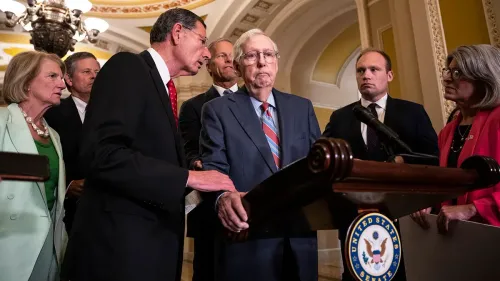Senator Mitch McConnell appears frail as a colleague speaks to him at a US Senate podium.