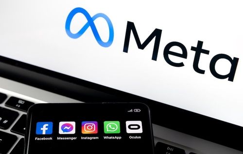 Smartphone displaying Meta apps with the Meta logo on a laptop screen in the background.